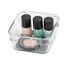 Drei Nagellackfläschchen und ein Make-up-Döschen in einem durchsichtigen Organizer