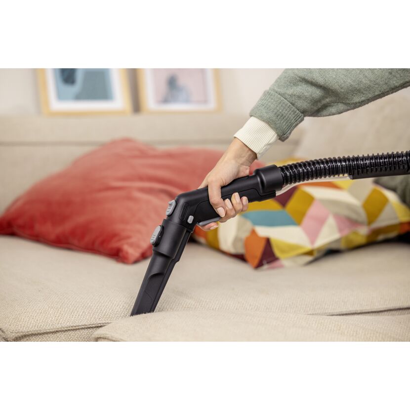 Person reinigt Sofa mit Waschsauger