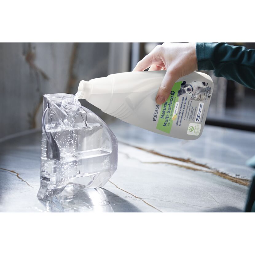 Bissell Natural Multi-Surface Reiniger wird in einen Wassertank gegossen.