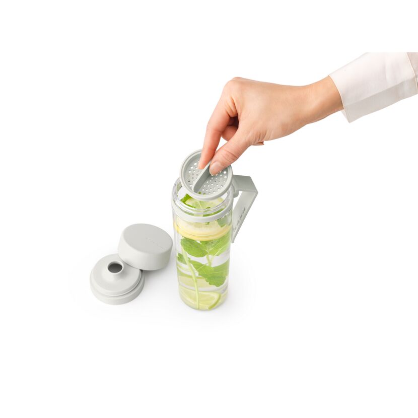 Person hält Sieb über Trinkflasche mit Wasser, Zitrone und Minze