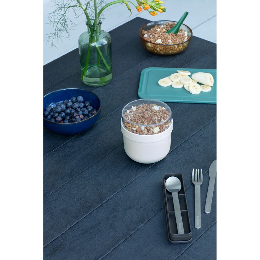Frühstücksschale mit Müsli, Bananen, Blaubeeren und Besteck