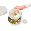 Person hält einen Salatschüssel-Deckel mit drei Fächern über einer Salatschüssel.