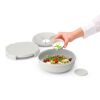 Person gibt Dressing über einen Salat in einer Salatschüssel