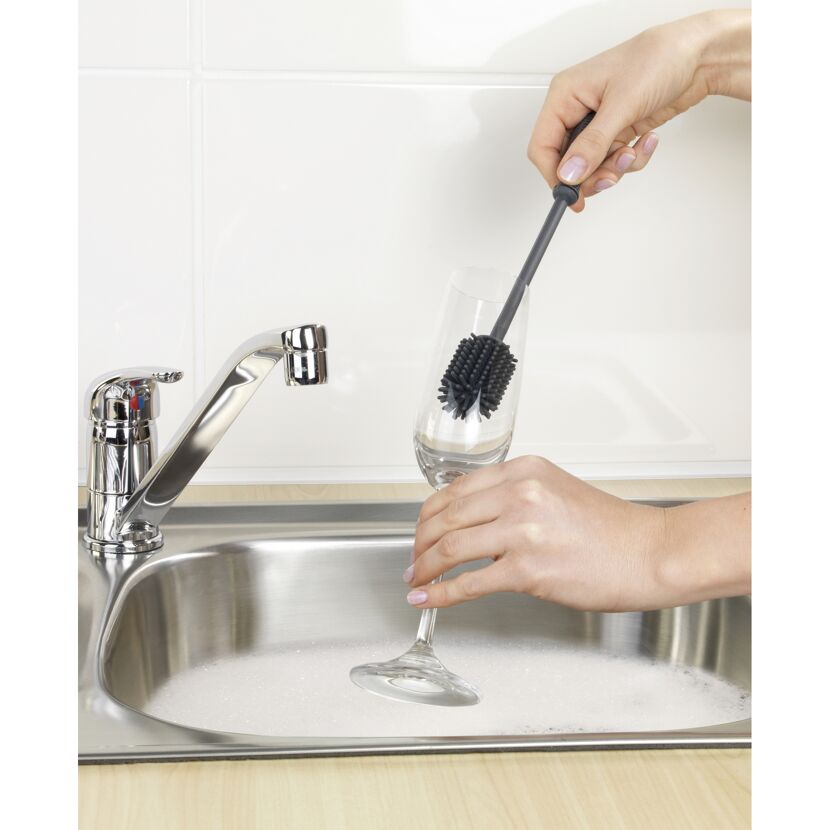Glas mit Bürste in Spüle reinigen