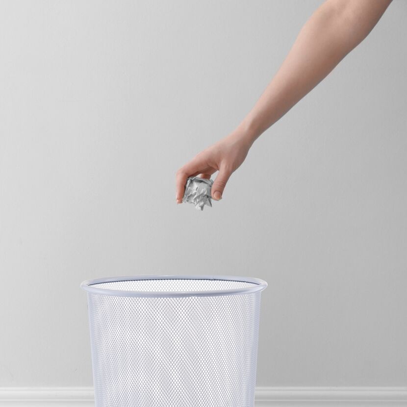 Hand wirft Papier in Mülleimer