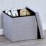 Grauer Sitzhocker mit Schuhen und Handtasche