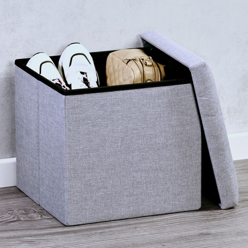 Grauer Sitzhocker mit Schuhen und Handtasche
