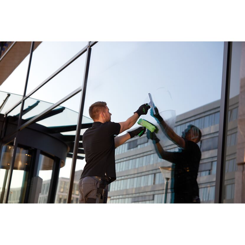 Person reinigt Fenster mit Abzieher.
