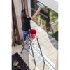 Person reinigt Fenster mit Abzieher auf Alu-Leiter