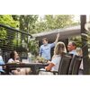 Person öffnet Sonnensegel über einer Gruppe am Tisch