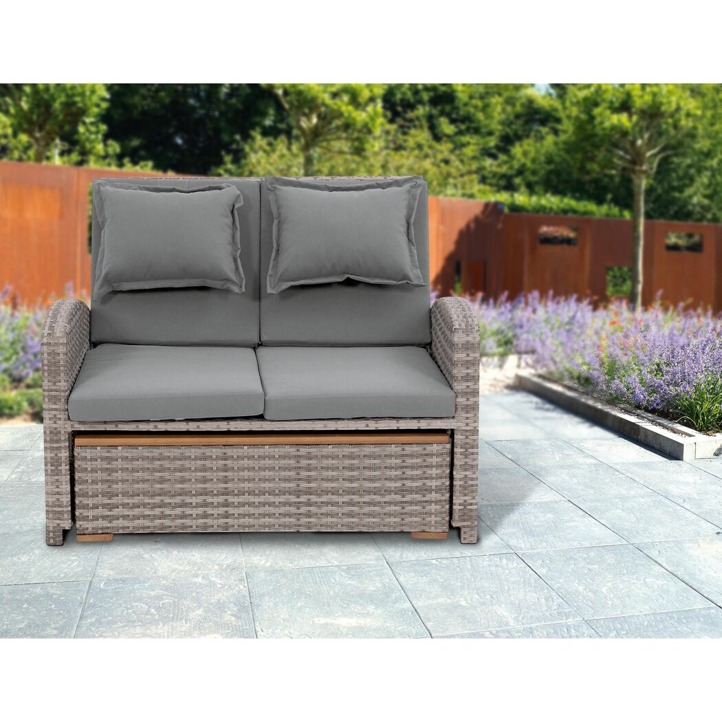 Graues Rattansofa mit zwei Kissen im Garten