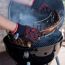 Person trägt Grillhandschuhe und entnimmt Rippchen vom Grill.