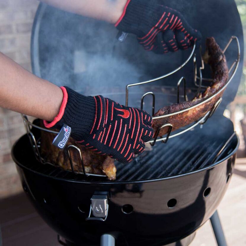 Person trägt Grillhandschuhe und entnimmt Rippchen vom Grill.