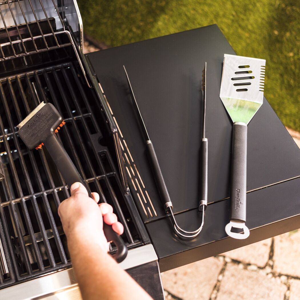 Person reinigt einen Grillrost mit einer Grillbürste.
