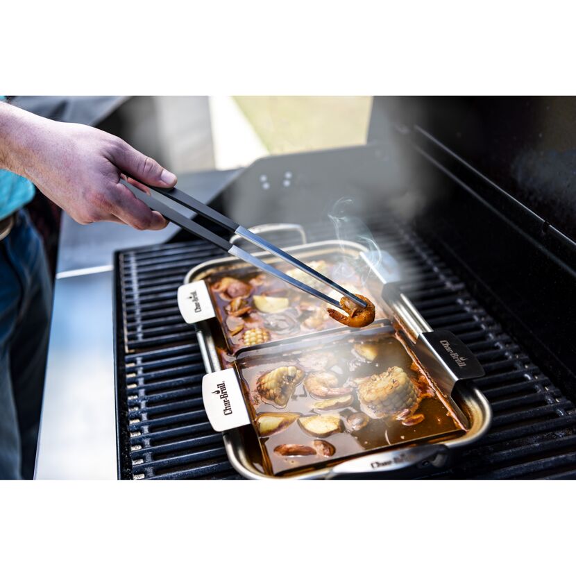 Person grillt Garnelen mit Grillzange