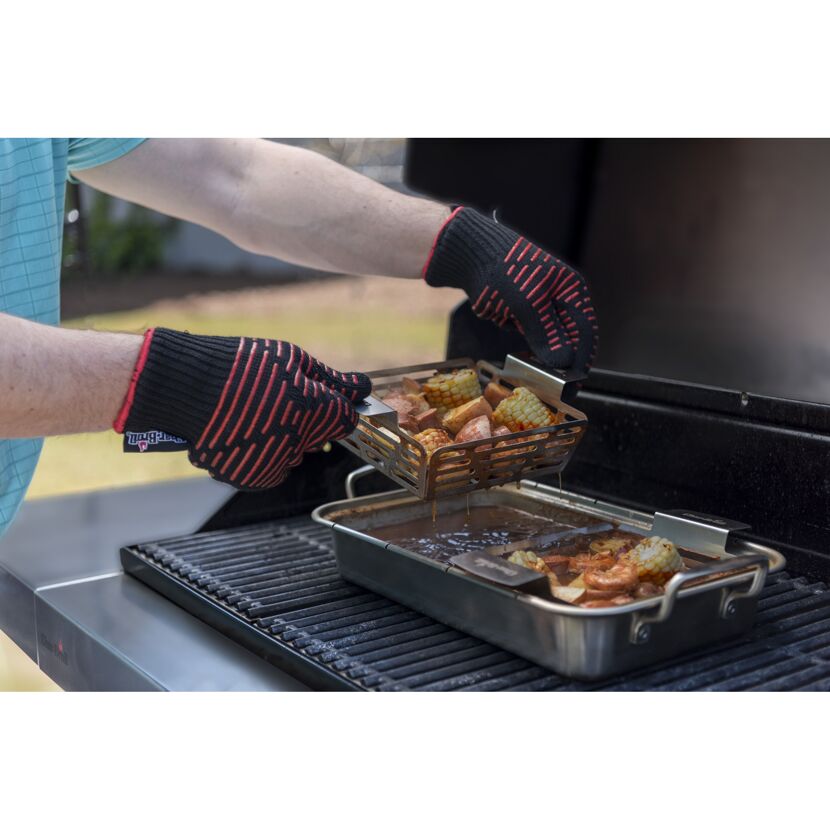 Person hebt Grillkorb mit Grillgut vom Grill