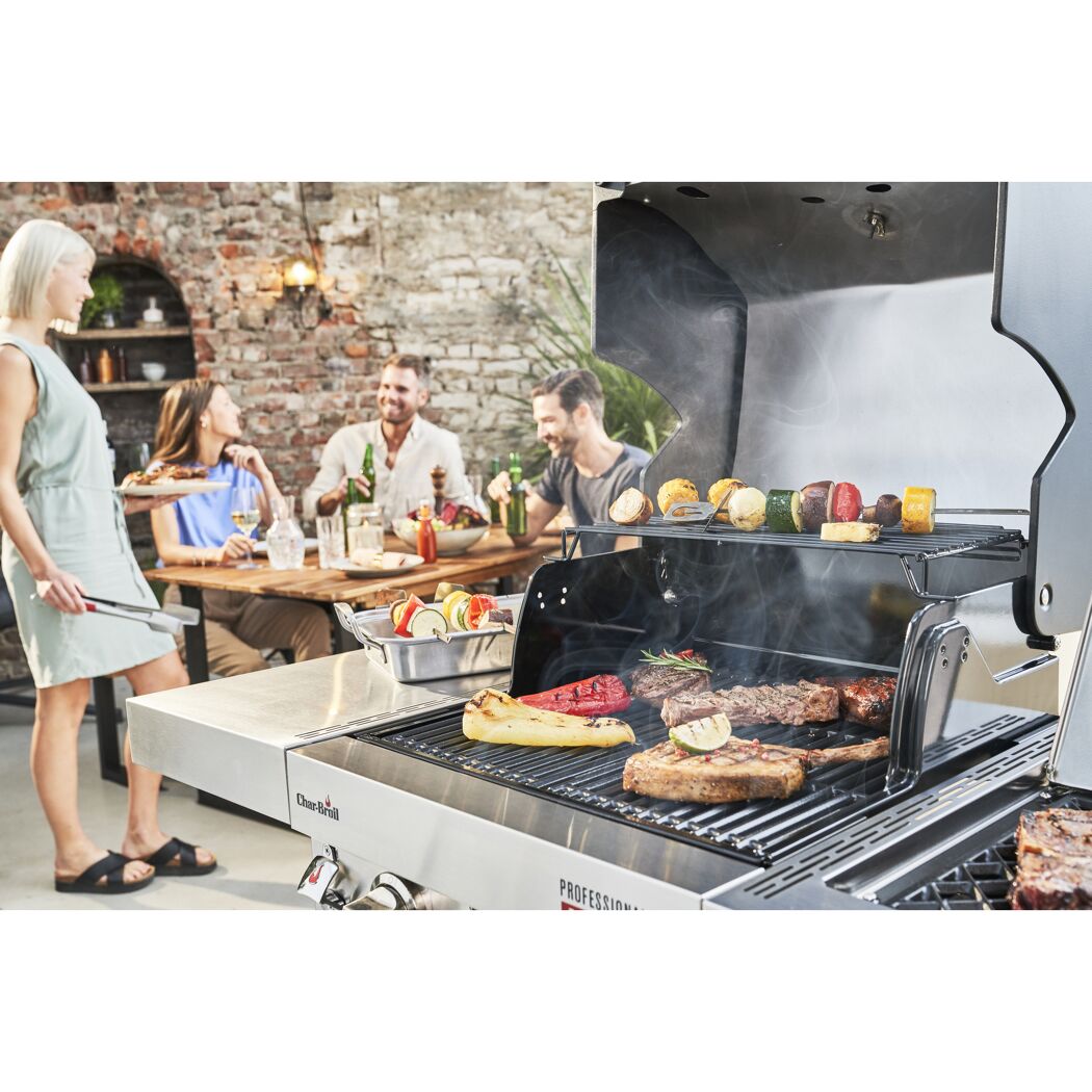 Personen grillen Steaks, Paprika und Gemüsespieße auf einem Gasgrill.