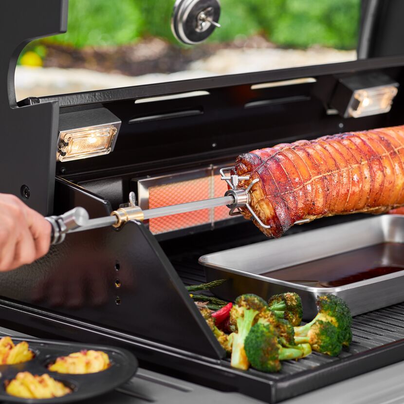 Person grillt Rollbraten mit Drehspieß