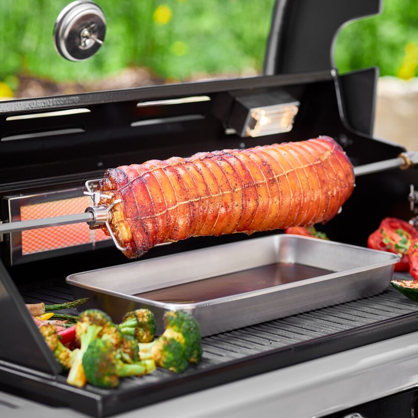 Rollbraten am Drehspieß auf dem Grill mit Gemüse
