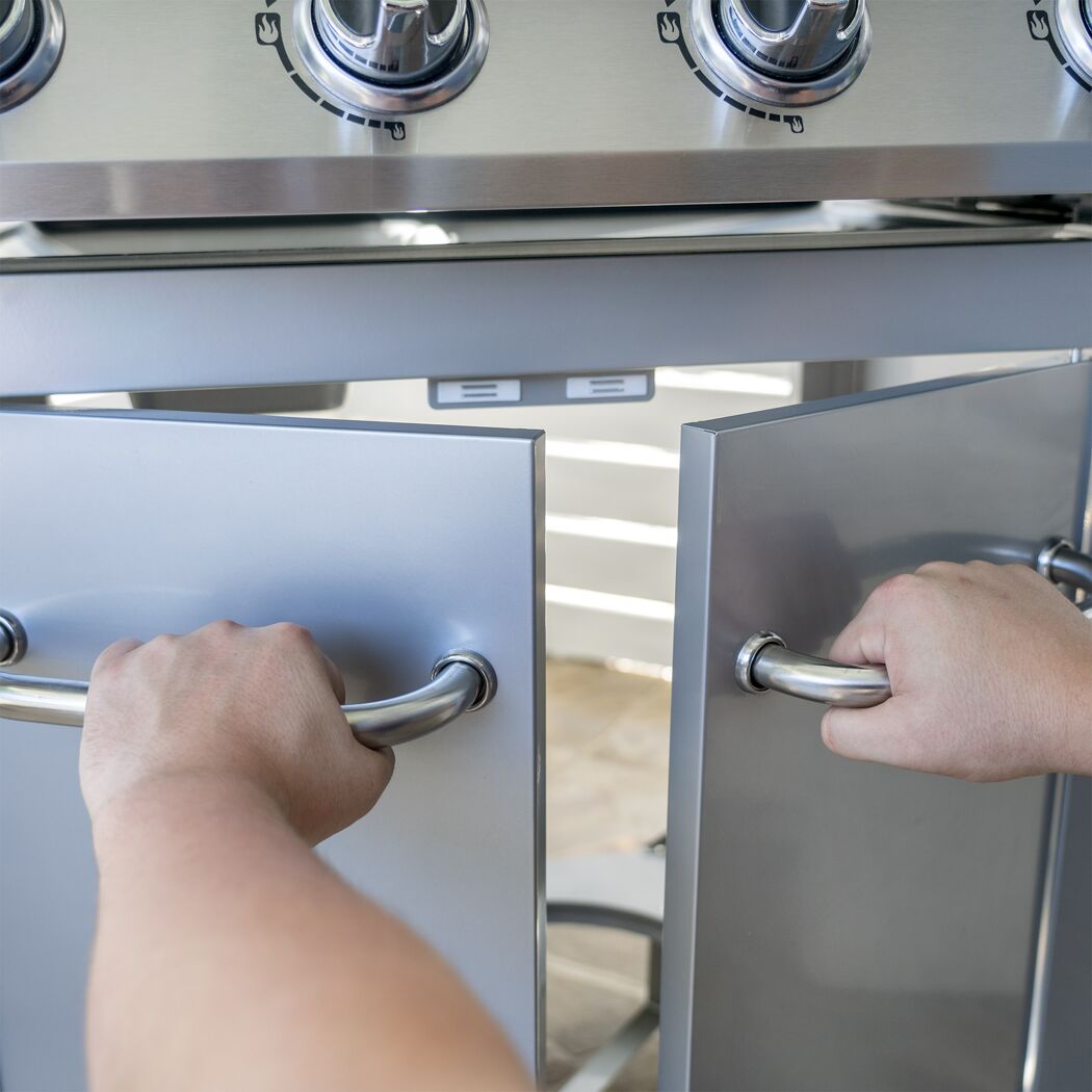 Person öffnet die Schranktüren eines Gasgrills.