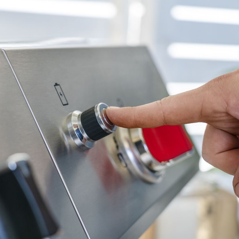 Person dreht einen Knopf am Gasgrill