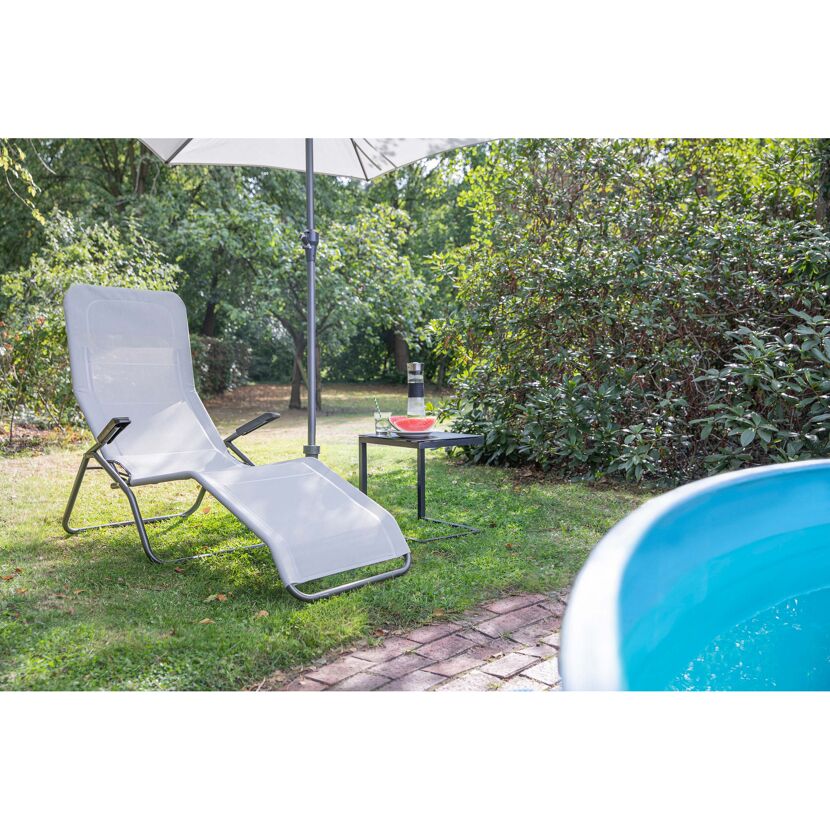 Graue Gartenliege unter Sonnenschirm neben Pool
