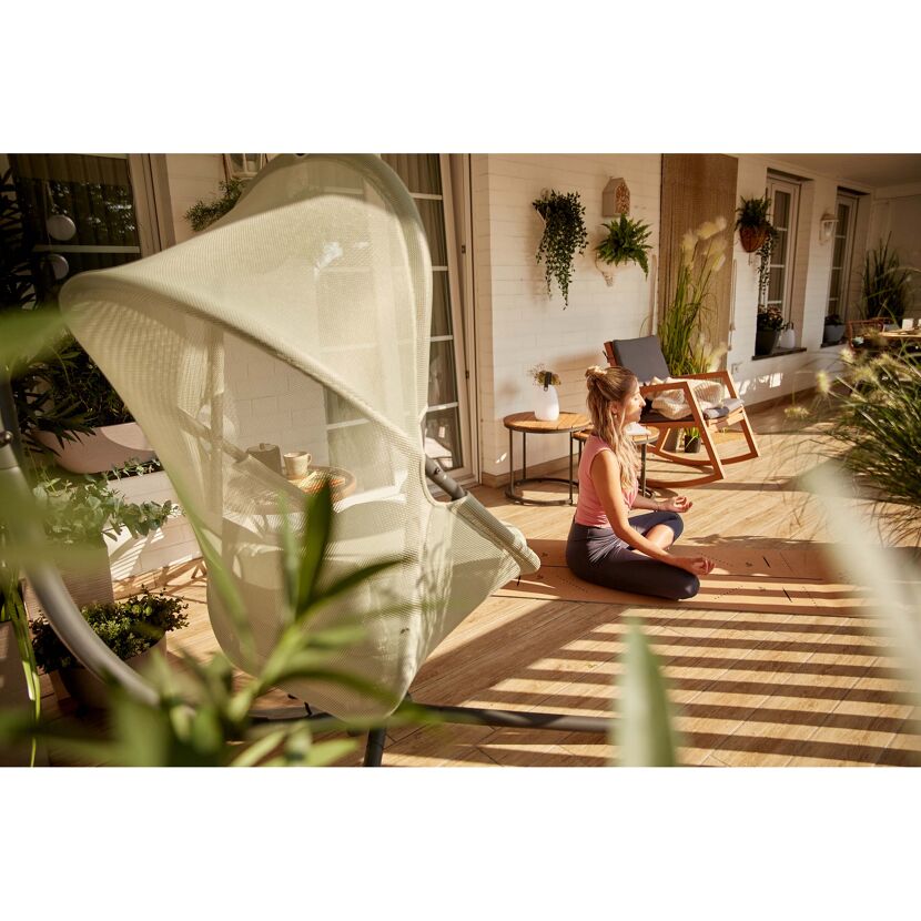 Person meditiert auf einer Yogamatte auf dem Balkon.