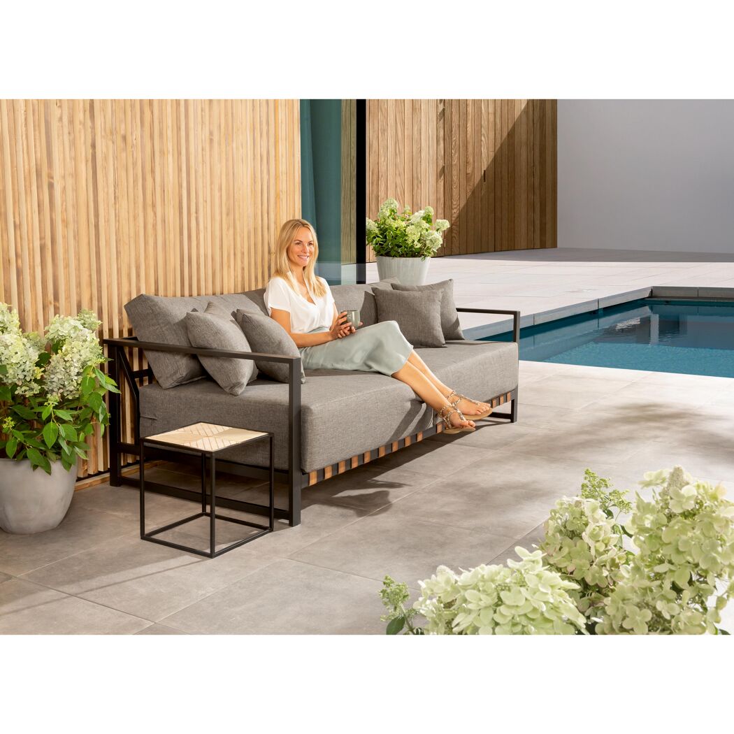 Person sitzt auf Gartensofa am Pool