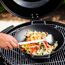 Person wendet Gemüse im Wok mit einem Woklöffel.