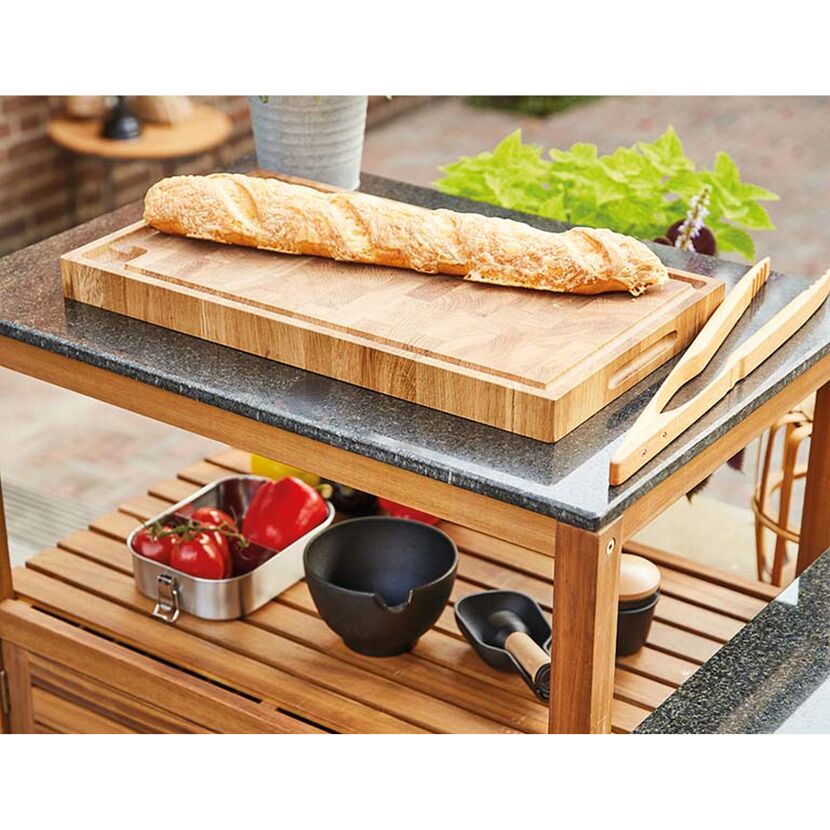 Baguette auf einem Holzbrett und eine Grillzange