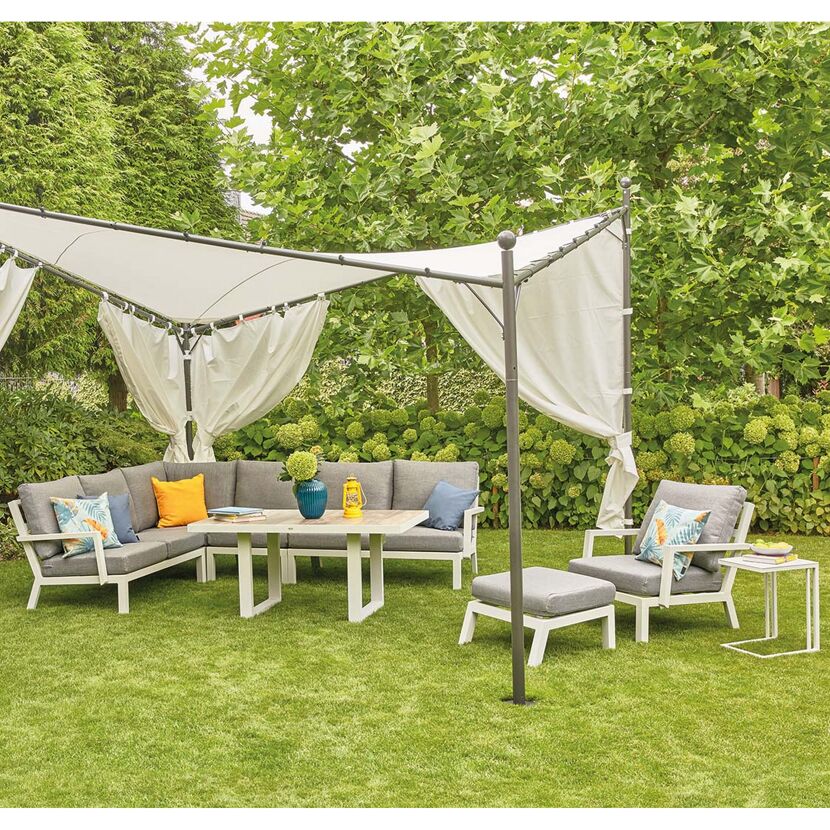 Weiße Gartenmöbel unter einem Sonnensegel mit Vorhängen