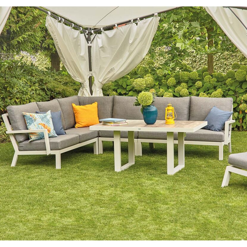 Weiße Gartenmöbel unter einem Pavillon mit Vorhängen.
