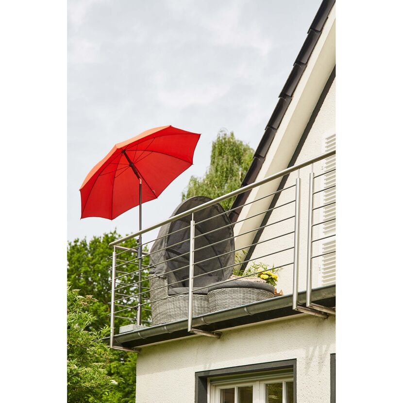 Roter Sonnenschirm und graue Loungeinsel auf einem Balkon