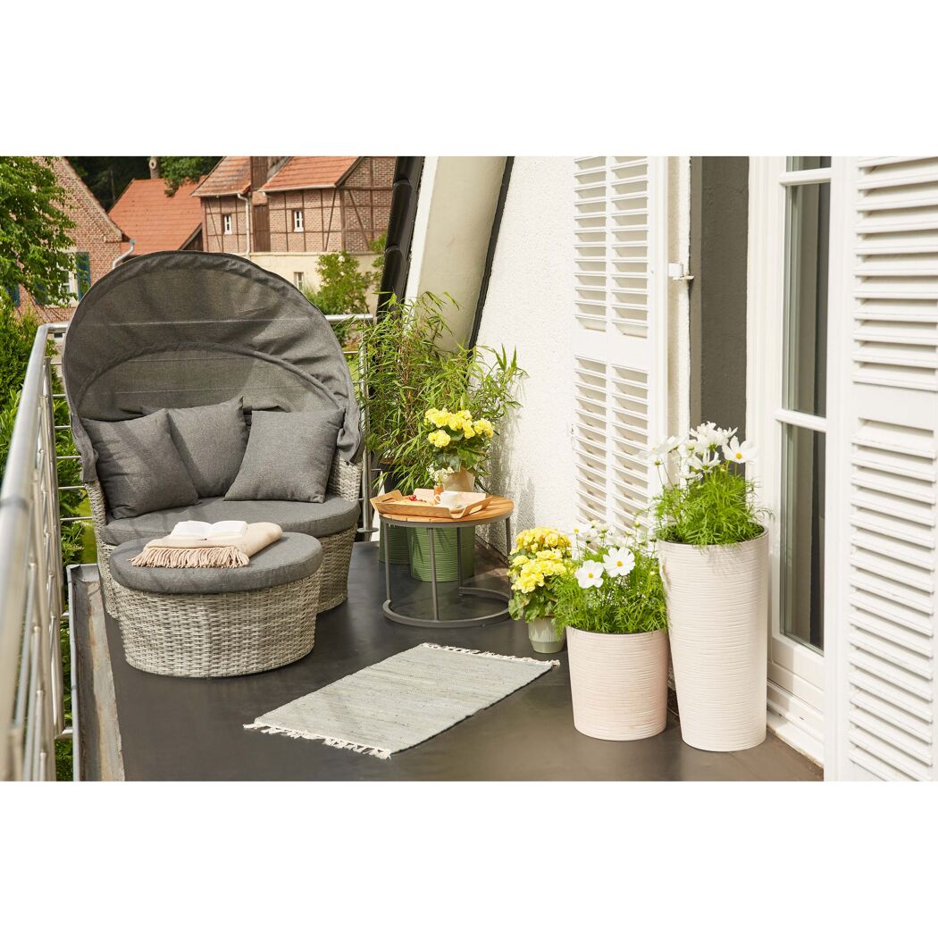 Gemütliche Loungeinsel auf einem Balkon mit Pflanzen.