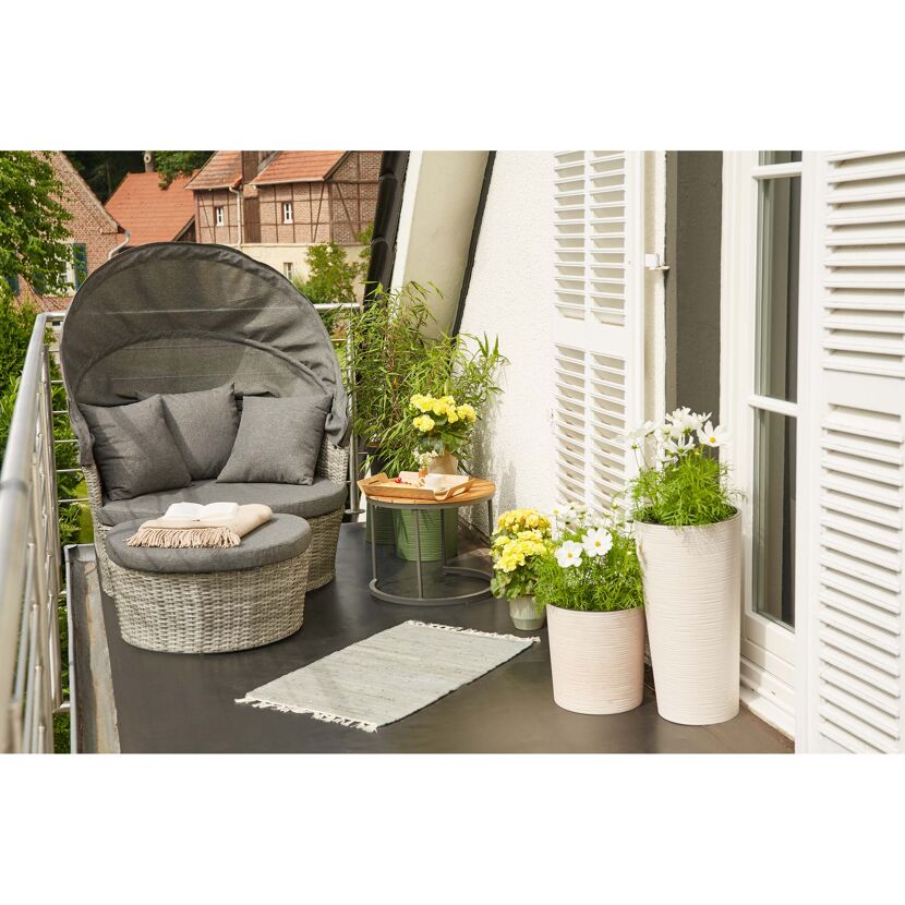 Gemütliche Loungeinsel auf einem Balkon mit Pflanzen.
