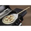 Pizza mit Pizzaschieber auf Grill