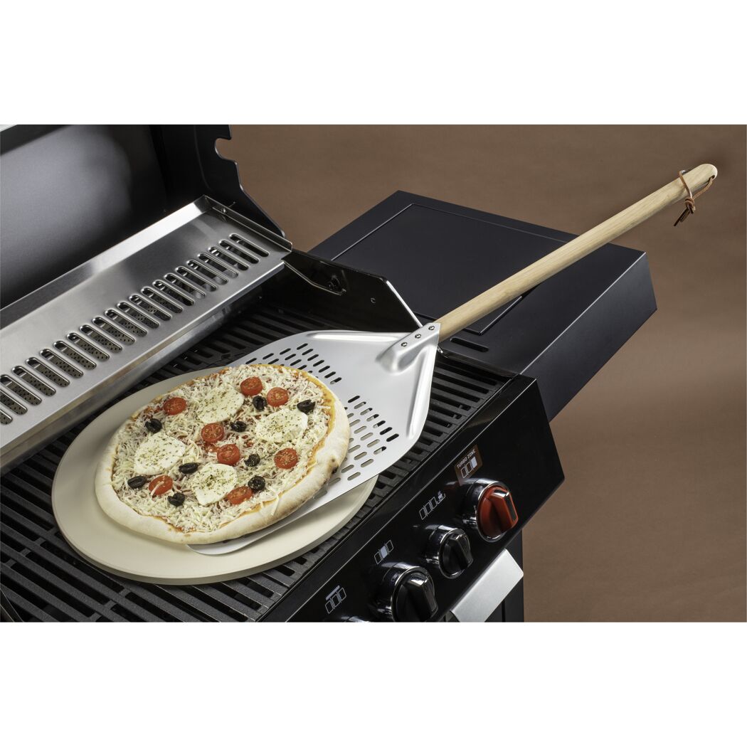 Pizza mit Pizzaschieber auf Grill