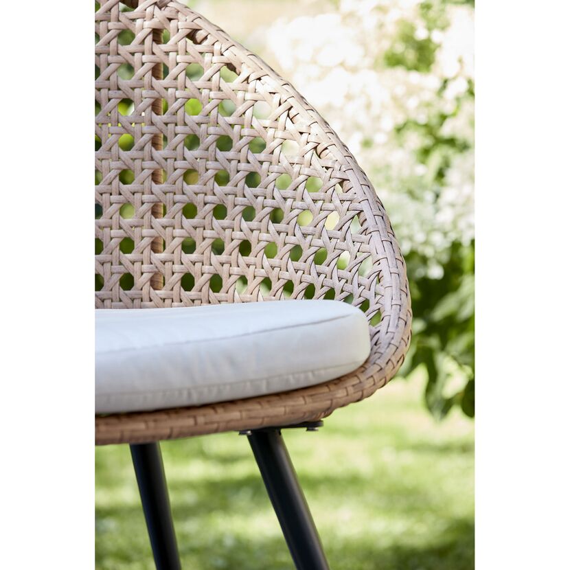Nahaufnahme eines geflochtenen Gartenstuhls mit Sitzkissen