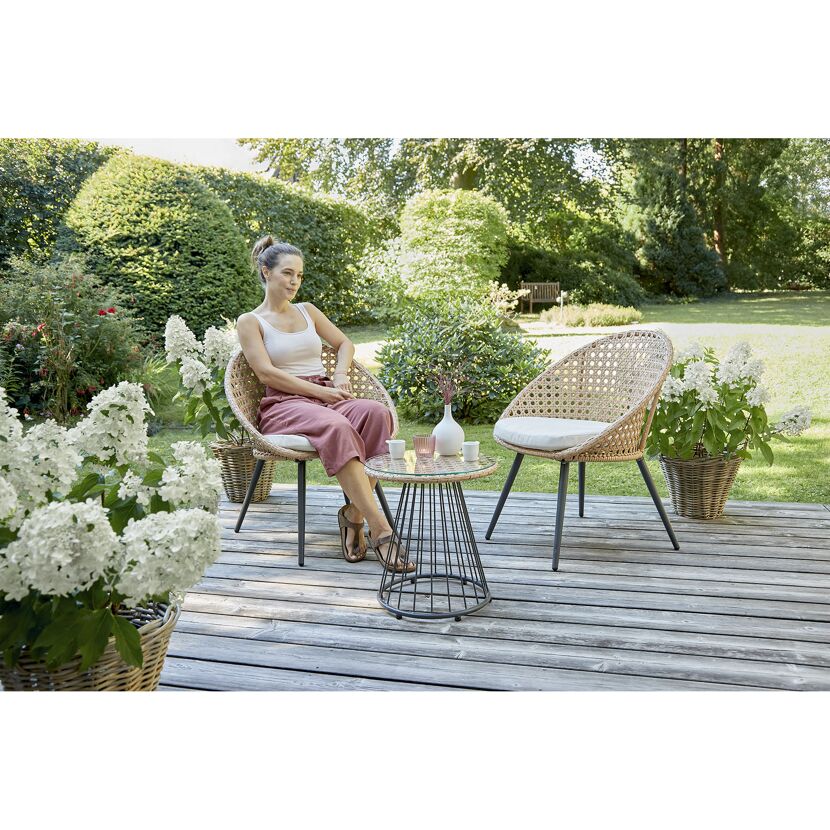 Person sitzt in einem Gartenmöbelset aus Polyrattan.