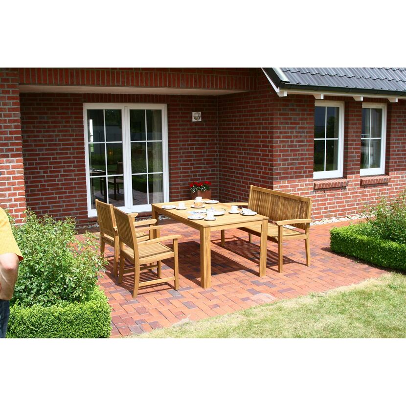 Holztisch mit Stühlen und Bank auf gepflasterter Terrasse