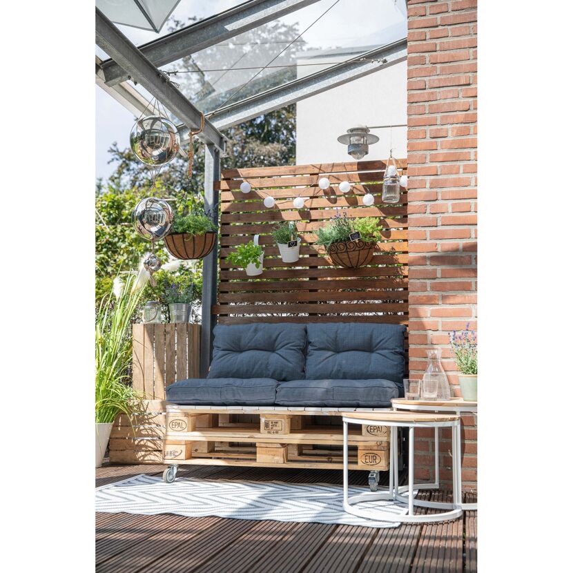 Gemütliche Sitzecke auf dem Balkon mit Palettenmöbeln, Pflanzen und Deko.
