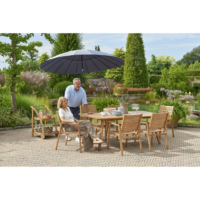 Zwei Personen sitzen an einem Gartentisch mit Sonnenschirm.
