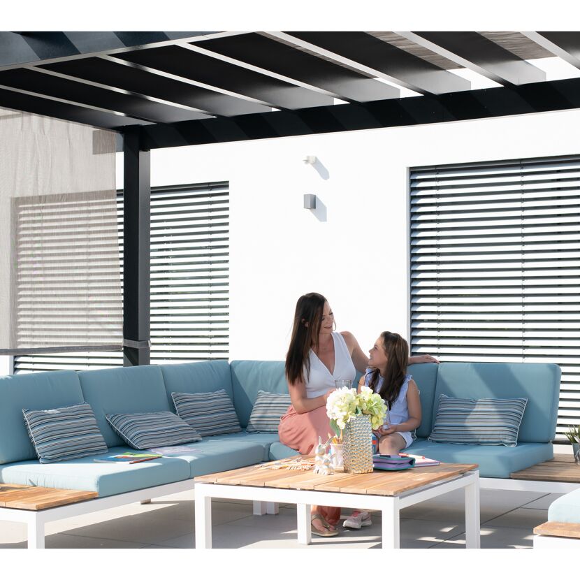 Zwei Personen sitzen auf einer Gartensofa unter einer Pergola.