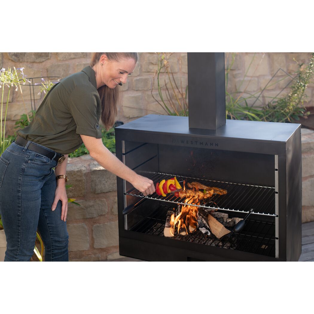 Person grillt Fleisch und Gemüse auf einem schwarzen Westmann Grill.
