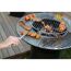 Person grillt Fleisch und Gemüse auf einem Grill.