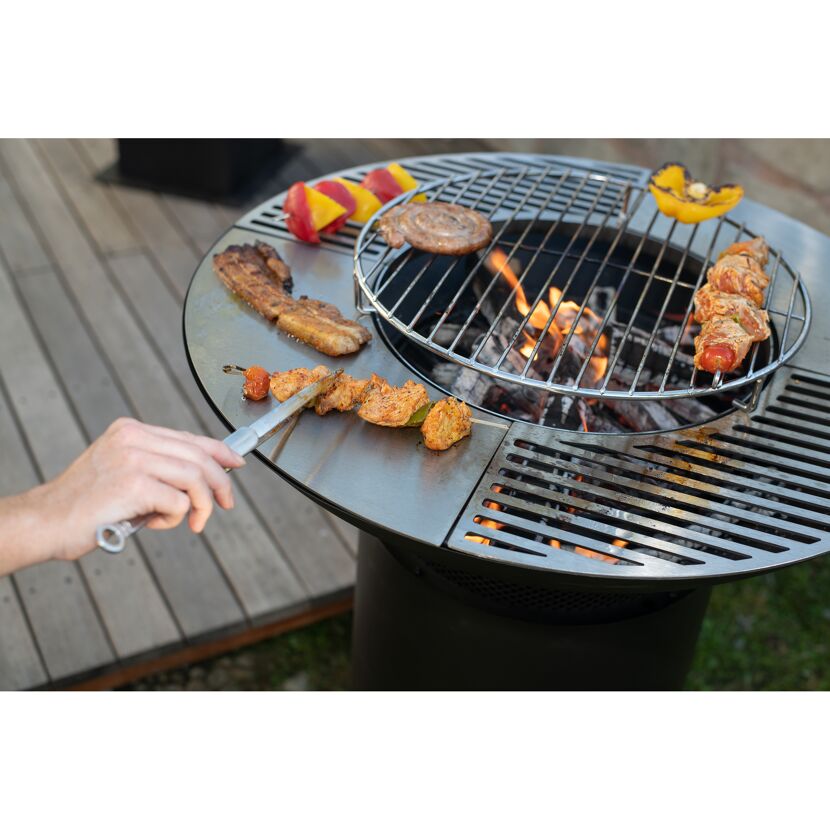 Person grillt Fleisch und Gemüse auf einem Grill.