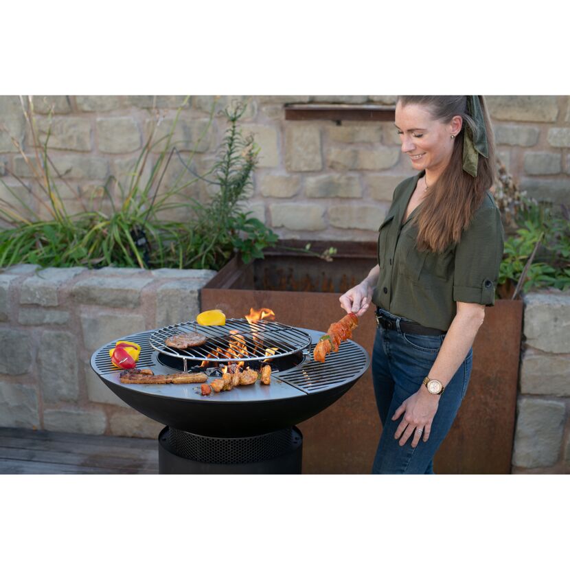 Person grillt verschiedene Speisen auf einem Grill.
