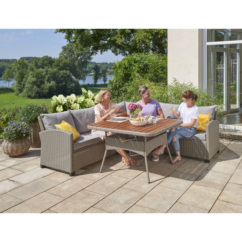 Drei Personen sitzen an einer Gartenlounge und essen.