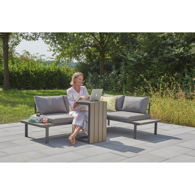 Person sitzt auf einer Gartenlounge und arbeitet am Laptop