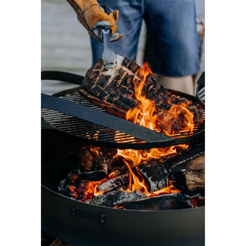 Person grillt Fleisch mit Grillzange
